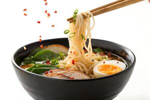 chopsticks are holding a bowl of ramen with eggs and meat photo