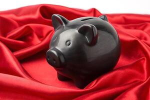 a black piggy bank sitting on a red satin cloth photo
