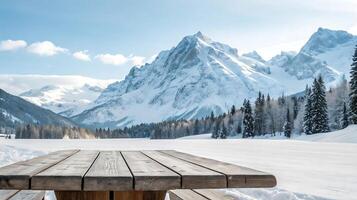 a wooden picnic table in the snow with mountains in the background photo
