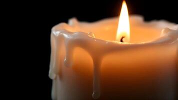 A close-up shot of a lit white candle with melted wax dripping down its sides, against a dark background, creating a peaceful ambiance photo