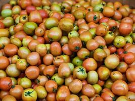 Fresh Tomatoes in Various Ripeness Stacked in a Market Stall photo