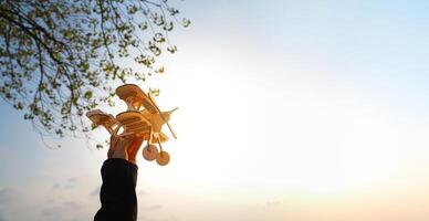 A person is holding a model airplane in the air. The sky is blue and the sun is shining brightly. photo