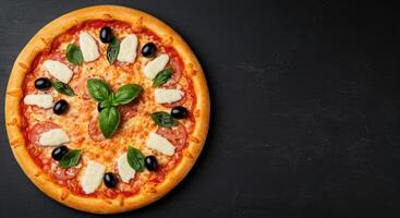 Pizza with cheese, olives and basil on a black background photo