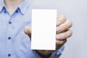 White business card in male hand with copyspace. Ideal for modern branding, message, contact, networking, design, corporate promotion, clean layout, marketing material, and identity. photo