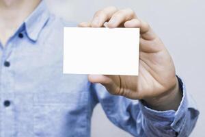 Close up of male hand showing plain business card. Perfect paper mockup for branding, identity, contact info, promotion, business connection, message, marketing, work, professional use. photo
