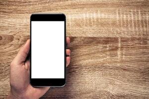 Man holding smartphone with Mockup image white screen On Wooden Table With beautiful patterns, copy space for adding content. Smartphone concept, lifestyle, clipping path photo