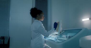 Work in a medical laboratory. A woman in a lab coat, disposable gloves and safety glasses sets up a blood splitting device using a screen - device photo