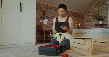 A woman selects tools from a toolbox by assembling a rack while sitting on the floor at home - assembling photo