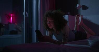 A man uses a mobile phone lying on the bed. Dark room, home interior - mobile - uses photo
