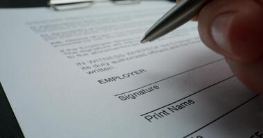 A man puts his signature on an employment contract, close-up of his signature, an unrecognizable person - unrecognizable photo