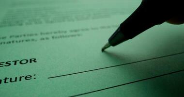 The man puts his signature on the document on behalf of the investor, close-up of his signature, an unrecognizable person photo