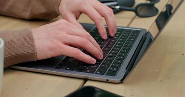 A man is typing on a laptop sitting at a table. Close-up of his hands, an unrecognizable person - sitting photo