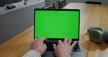 Close-up of a woman's hands while she typing on a laptop with a green screen. Front view of the screen. Copy space, mockup photo