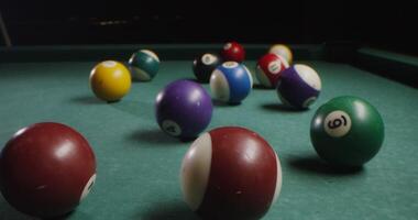 Multi-colored billiard balls in a chaotic manner lie on the billiard table, slow shooting without moving objects, without people in the frame - billiard photo