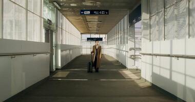 A woman in a coat with luggage in her hand stands at the railway station. She looks at the camera with a serious look - railway photo