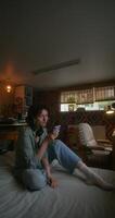 A young woman uses a mobile phone while sitting on a bed at home with a depressed look - depressed photo