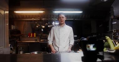 A man in a chef's uniform records the cooking process on , standing near a frying pan in the kitchen of a restaurant - cooking photo
