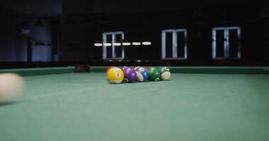 White billiard ball breaks a triangle of colored balls that fly to the sides, one ball flies into the hole, close-up, no people in the - triangle photo