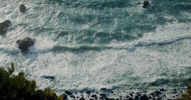 Top view of the rocky seashore, foamy waves beating against rocks, reef in shallow water - beating photo