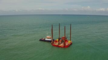 The boat is moored near a small offshore platform not far from the shore with sheer limestone cliffs and a lighthouse. Drone , Etretat, France - platform photo