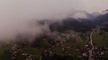 The drone flies high above the clouds, offering a view of the village at the foot of the Alps. filming in the evening from a bird's eye view. Austria, Alps - filming photo