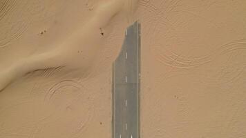 Top view of a modern paved road covered with sand, laid in the middle of the desert - middle photo