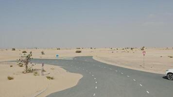 Drone view of a white SUV driving along a modern paved road covered with desert sand photo