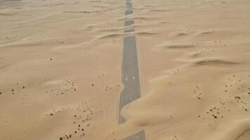 Top view of a modern paved road covered with sand, laid in the middle of the desert photo