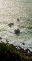 Top view of the rocky seashore, foamy waves beating against rocks, reef in shallow water photo