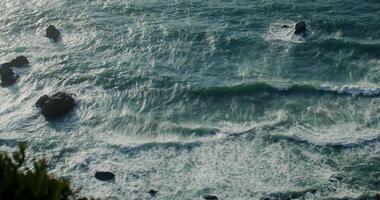 Top view of the rocky seashore, foamy waves beating against rocks, reef in shallow water - against photo
