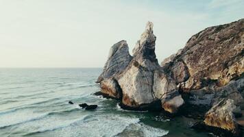 Rocks sticking out of the water on the seashore, drone view from the sea photo