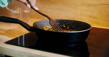 Close-up of a frying pan during cooking. A woman's hand stirs the string beans with a spatula - string photo