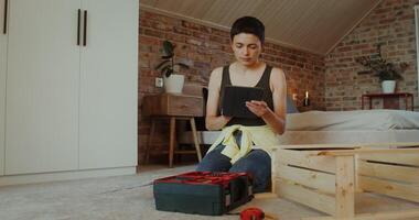 A woman selects tools from a toolbox by assembling a rack while sitting on the floor at home photo