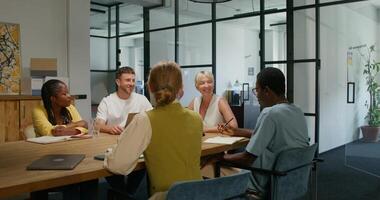 A group of young people are smiling and talking while sitting in an office meeting. Business planning, startup photo