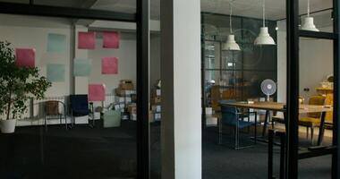 General view of a modern office. Empty boxes are lying near the wall. Two women are talking as they pass by. Daylight - talking photo