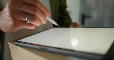 The man signs with a stylus on the tablet confirming receipt of the parcel. close-up of his hands, an unrecognizable person - unrecognizable photo