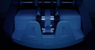 The calculating machine counts a stack of dollar bills on a dark background, front view, close-up photo