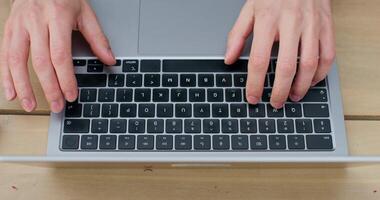 A man is typing on a laptop sitting at a table. Close-up of his hands, an unrecognizable person photo