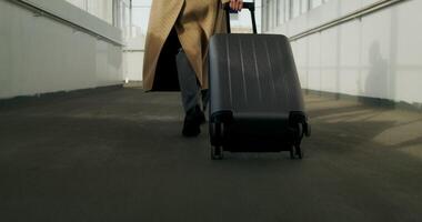 A woman in a coat with luggage in her hand walks down the corridor of a public building, close-up of her legs, an unrecognizable person - public photo