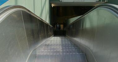 A woman in formal clothes is talking on a mobile phone. She rides the escalator coming up from the subway station - talking photo