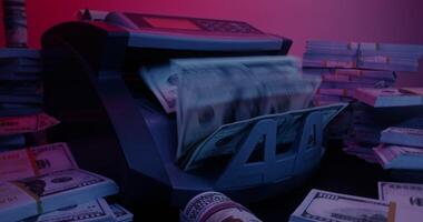 The calculating machine counts a stack of dollar bills. Bundles of money are lying around on the table photo