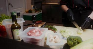 A woman in a chef's uniform with disposable black gloves on her hands cuts cabbage in the restaurant kitchen, close-up of her hands, no face - gloves photo