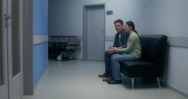 Concerned patient's relatives are waiting sitting on the couch in the hospital corridor - hospital photo