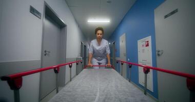 A vie at nurse who carries an empty gurney covered with a disposable sheet down the hospital corridor photo