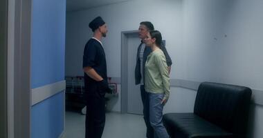 The doctor informs the relatives of the disappointing result of the operation, they cry, standing hugging in the hospital corridor photo
