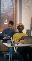 A man and a woman use laptops working at desks in the office. A man in a hat and headphones is chatting on chat and playing with a baseball - chatting photo