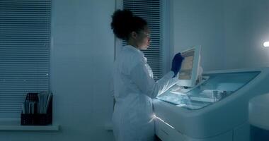 Work in a medical laboratory. A man and a woman are talking using a laptop sitting at a table with a microscope. A woman sets up a blood splitting device photo