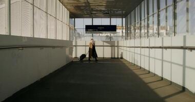 A woman in a coat with luggage in her hand walks through the railway station with a concentrated look photo
