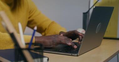 A man typing on a laptop keyboard, sitting at a desk in the office, close-up of his hands - typing photo