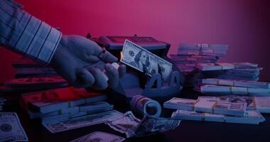 A man's hand sets fire to a dollar bill lying in a counting machine using a lighter. Bundles of money are lying around on the table photo